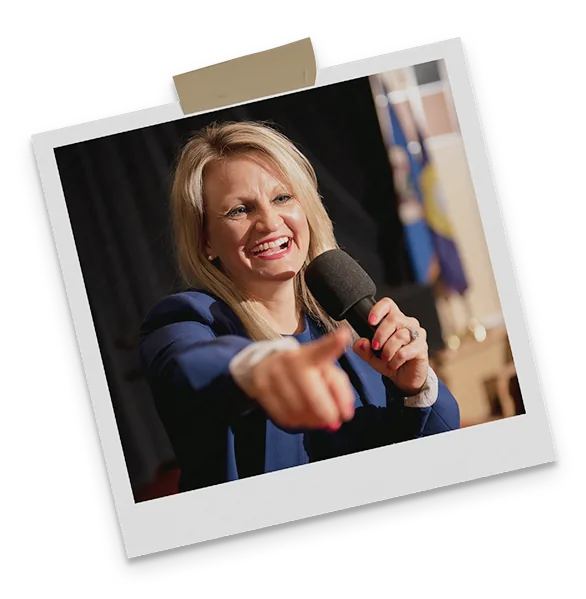 A keynote speaker on stage mid-talk, pointing towards the audience.